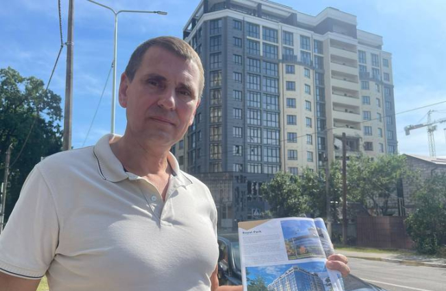Un ciudadano ucraniano muestra el proyecto de un edificio que puede verse detrás de él. LA 8 TELEVISIÓN