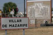 Cartel anunciador de la localidad de Villar de Mazarife, con la pista de futbito al fondo