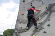 Un niño practica escalada en un rocódromo, agarrado por una cuerda para garantizar su seguridad