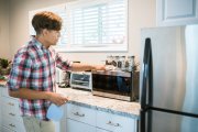Hombre pone en orden y deja los electrodomésticos de la cocina antes de las vacaciones.