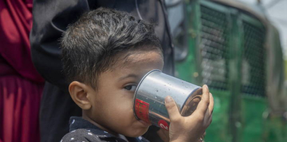 Un niño bebe agua en un tanque junto a una carretera en Dhaka (Bangladesh).