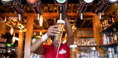 Una camarera sirve unas cervezas en un bar.