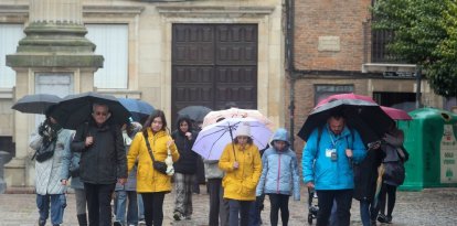 Un grupo de turistas escuchaba ayer a uno de los guías de León, en medio de la lluvia y la nieve.