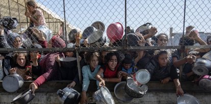 Palestinos desplazados se agolpan frente a un comedor social para recibir raciones de alimentos al sur de la Franja de Gaza. EFE/ Haitham Imad.