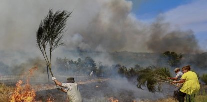 Tres vecinos intentan extinguir las llamas de una zona durante un incendio forestal en Sao Pedro e Santa Maria, Trancoso, Portugal.