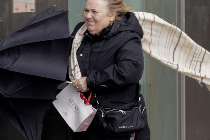 Una mujer se resguardaba de la fuerza del viento en A Coruña durante el paso de la borrasca Karlotta.