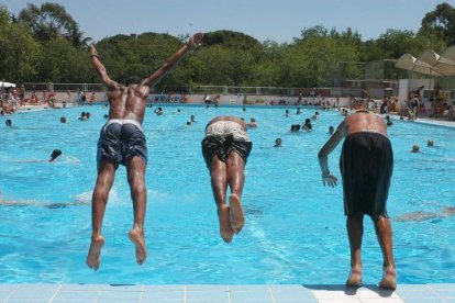 Tres jóvenes se lanzan a la piscina en una intensa jornada de calor veraniego. KIKO HUESCA
