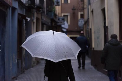 Una mujer se protege de la lluvia con un paraguas.