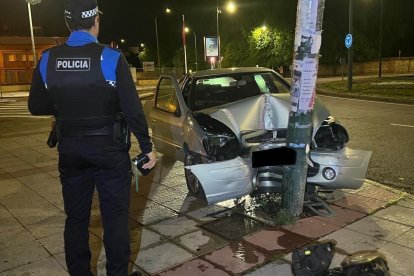 Un agente en la Policía Local junto al coche siniestrado.