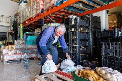 Uno de los voluntarios del Banco de Alimentos de León, ayer con las bolsas que se distribuyen a las familias. La reina Sofía, en el congreso de Santander, ayer.