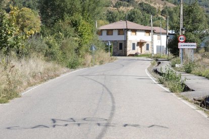 La carretera de entrada a Carrocera con una pintada en contra de volver a abrir la cantera.