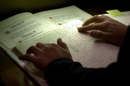 Un joven lee en braille los artículos de la Constitución española.
