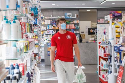 Un joven compra en una farmacia de León protegido por la mascarilla, ayer.