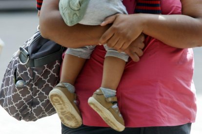 Una mujer sostiene a un bebé en brazos mientras pasea por la calle.