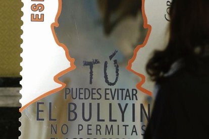Una joven observa un cartel contra el acoso escolar.