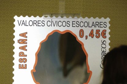 Una joven observa un cartel contra el acoso escolar.