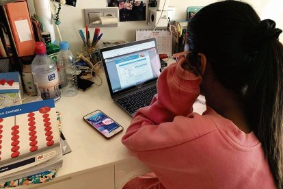 Una estudiante realiza las tareas con su ordenador y su teléfono móvil al lado.