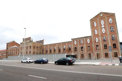 La fachada de la antigua Azcarera Santa Elvira luce ya sin andamios después de 16 años amparados los muros. A la derecha, imagen de las máquinas que trabajan este domingo para adelantar la entrega del trampantojo de lo que iba a ser el Palacio de Congresos de León.