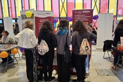 Cuatro chicas se acercan a Diaconía en la Expojoven para participar en el juego interactivos con información sobre la trata.