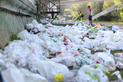Operarios del servicio de limpieza del Ayuntamiento de León retiran la basura acumulada en la orilla del Río Bernesga de la capital leonesa tras la noche de San Juan. CAMPILLO