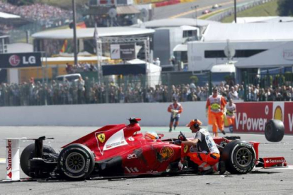 Técnicos del circuito atienden a Fernando Alonso después del choque múltiple. Foto: REUTERS / FRANCOIS LENOIR