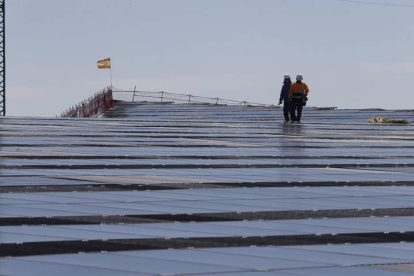 Dos operarios trabajan en un tejado cubierto de placas solares. RAMIRO