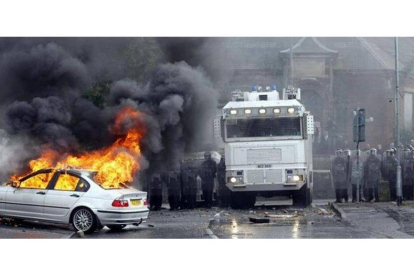 Un coche arde mientras la policía contempla la escena en Ardoyne, el jueves.