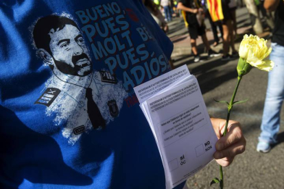 Una persona con la camiseta del mayor de los Mossos Josep Lluis Trapero y papeletas del referéndum del 1-O.