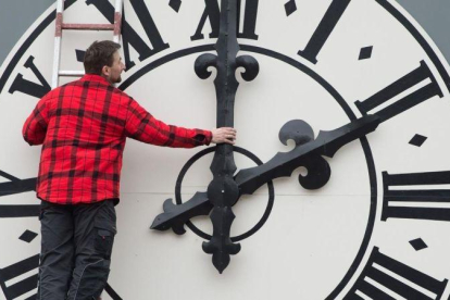 Un operario cambia las manecillas del reloj de una iglesia de Dresde, en Alemania.