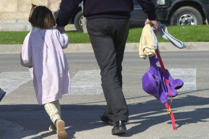 Un padre lleva a su hija de la mano tras recogerla a la salida del colegio.