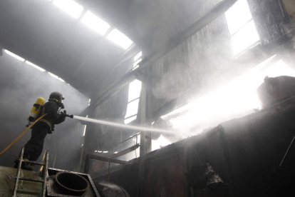 Un bombero trabaja en la extinción de un incendio en una fábrica de Villamañán, en 2013.