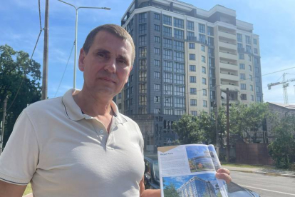 Un ciudadano ucraniano muestra el proyecto de un edificio que puede verse detrás de él. LA 8 TELEVISIÓN