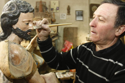 El leonés Jesús Fernández retoca una de las piezas para restaurar con las que trabaja en su taller, donde se dedica a un oficio que le viene de familia.