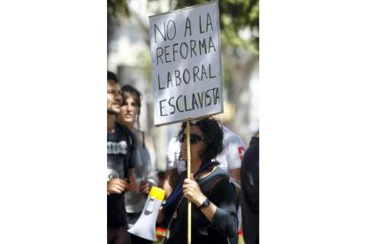 Una mujer muestra un cartel en contra de la reforma laboral del Gobierno. Foto: REUTERS