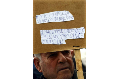 Un hombre se oculta bajo un cartel con sus reivindicaciones durante la protesta celebrada en Madrid. Foto: AGUSTÍN CATALÁN