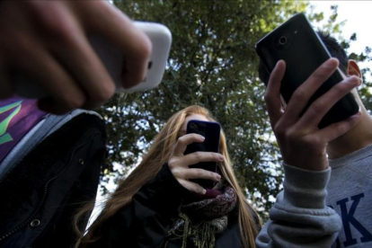 Unos adolescentes utilizan su teléfono móvil.