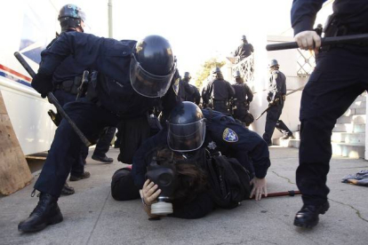 Agentes de la policía de Oakland arrestan a uno de los participantes en la protesta de indignados, el sábado, en el centro de la ciudad.