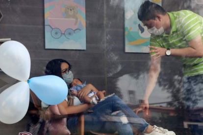Una joven pareja muestra a su hijo a la familia en Monterrey a través de un cristal por el covid. MARÍA JULIA CASTAÑEDA