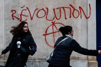 Dos jóvenes hacen una pintada en París. TERESA SUAREZ