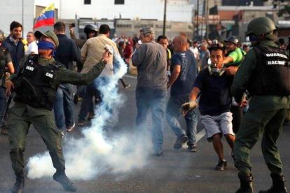 Un militar lanza un bote de gas lacrimógeno durante los disturbios en Caracas