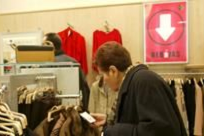 Una mujer observa atentamente la etiqueta de una prenda durante el primer día de rebajas