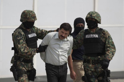Joaquin 'El Chapo' Guzman es escoltado por dos soldados mexicanos tras su detención.