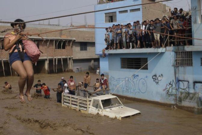 Una mujer es evacuada en una calle inundada de Lima.