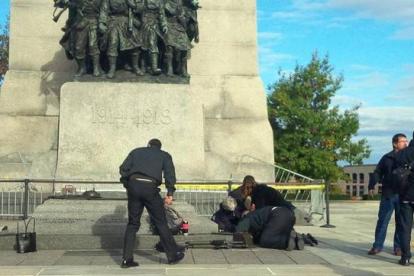 Unos soldados atienden a un compañero herido, ante el monumento de los veteranos de guerra en Ottawa.