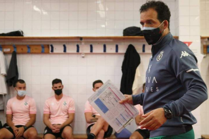 Ramón González dando instrucciones a sus jugadores en el interior del vestuario, todos ellos con la mascarilla puesta. DL