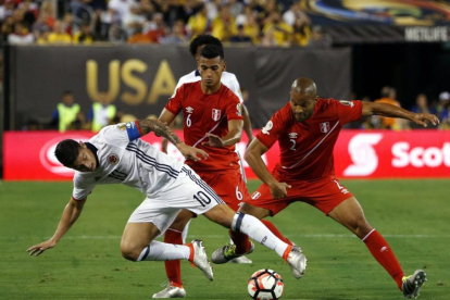 El colombiano James Rodriguez pugna por el balón con los peruanos Alberto Rodriguez y Miguel Trauco.