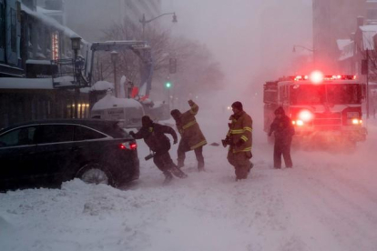 Un bombero ayuda a empujar un camión atrapado en la nieve.