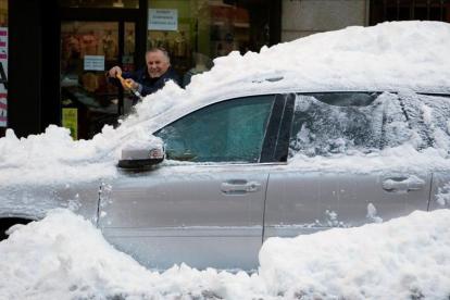 Un hombre limpia de nieve su coche atrapado por la nieve en una céntrica calle de Ávila, el pasado domingo.