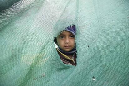 Una niña mira desde el agujero de una tienda en Katmandú, en el Nepal.