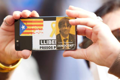 Imagen de una independentista con un carnet de Puigdemont, el miércoles, en una manifestación a las puertas de la Generalitat. ALEJANDRO GARCÍA